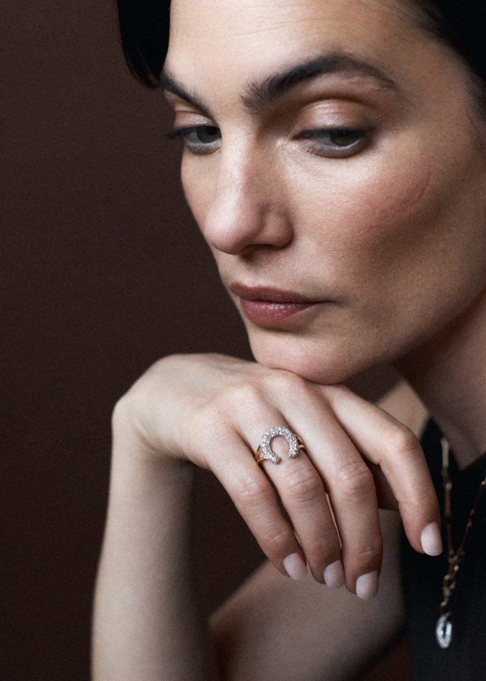 Close-up of a woman wearing a diamond horse shoe ring with a dark background