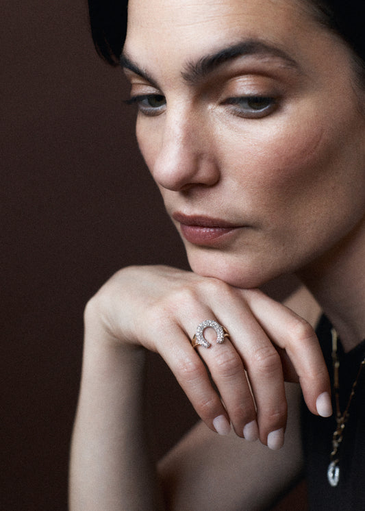 Close-up of a woman wearing a diamond horse shoe ring with a dark background